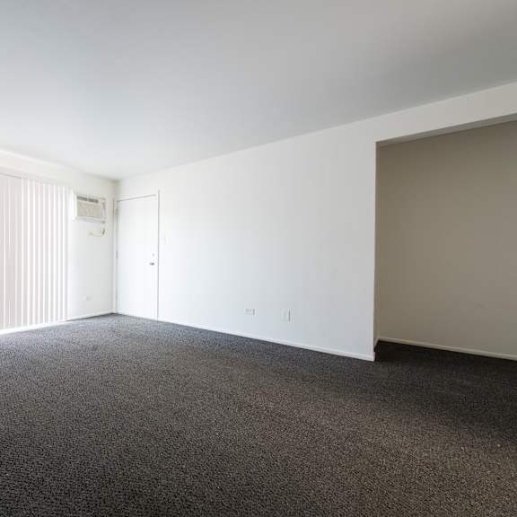 an empty living room with white walls and a window with white blinds