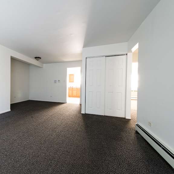 an empty living room with carpet and a white door
