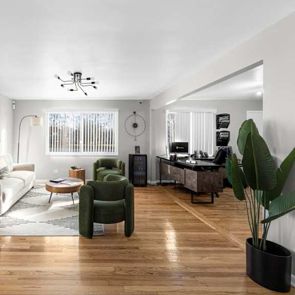 a living room with a white sofa, green armchair, and a wooden floor.