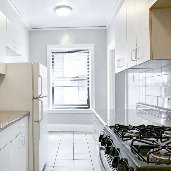 an empty kitchen with white cabinets and a window