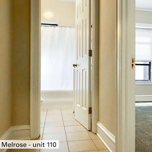 an empty living room with two windows and a ceiling fan