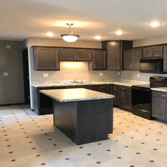 large kitchen with dark brown cabinets, center island and granite counter tops