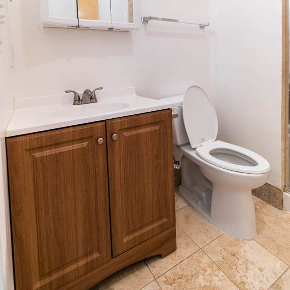 a white sink with a wooden cabinet and a toilet in a bathroom.