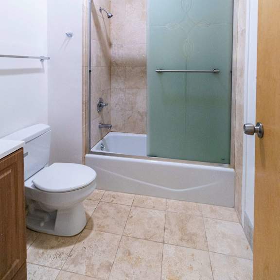a white toilet sits in a bathroom next to a walk-in shower.