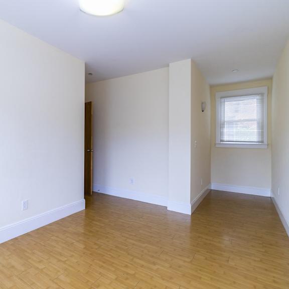 a room with a sliding glass closet door and wooden flooring.