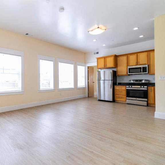 a kitchen with wooden cabinets, a refrigerator, and living room.