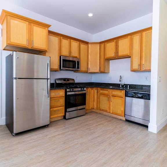 a kitchen with wooden cabinets, a refrigerator, and living room.