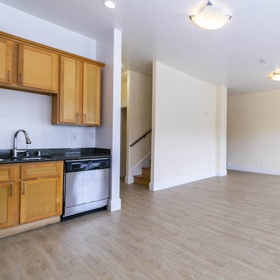 a kitchen with wooden cabinets, a refrigerator, and living room.
