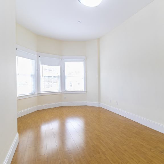 a room with wooden floor and windows.