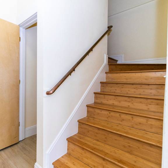 a wooden staircase with a white wall and a wooden door.