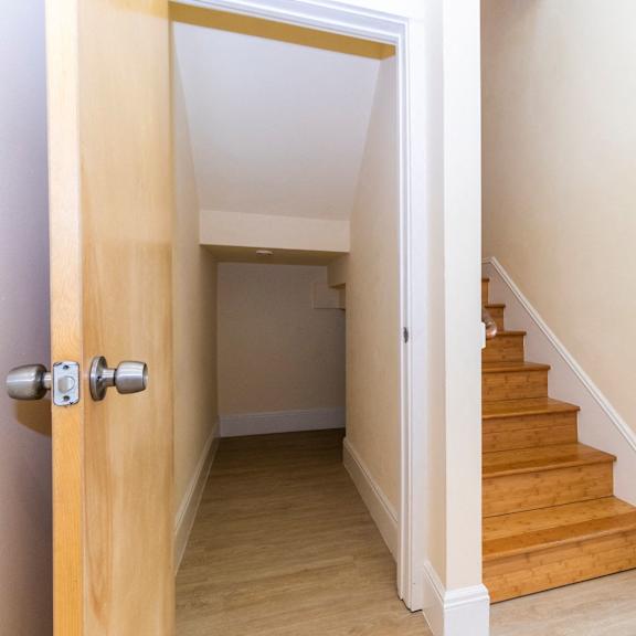 a wooden door opens to a hallway with a staircase.