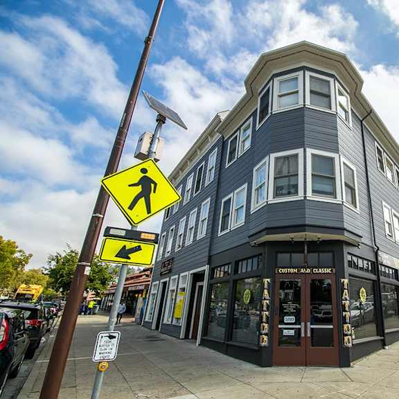a street view of 2597 telegraph with a pedestrian crossing sign.