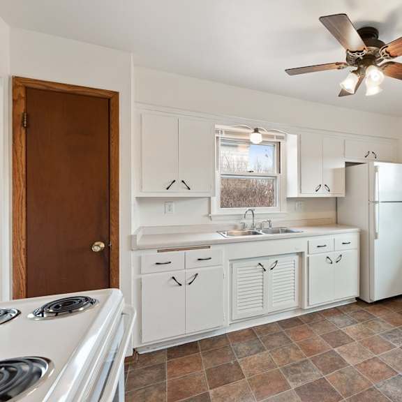 a kitchen with white cabinets and a white refrigerator