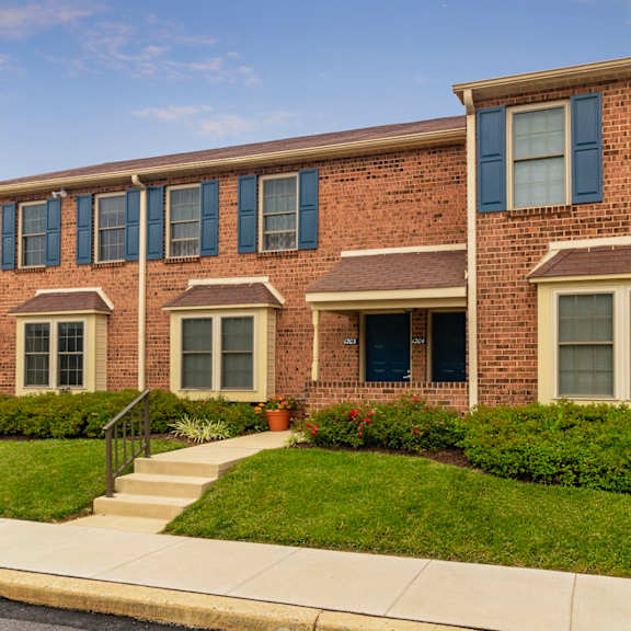 an exterior view of severgn apartments two-story buildings with well-maintained lawns, beautiful landscaping, and street lamps lining a sidewalk.