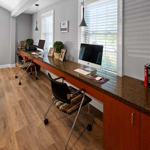 a resident business center with two computer stations, a long desk, and two windows in severgn apartments clubhouse.