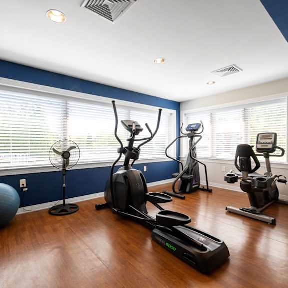 cardio machines, a gym ball, and a fan at our state-of-the-art fitness center with many large windows and plenty of light.