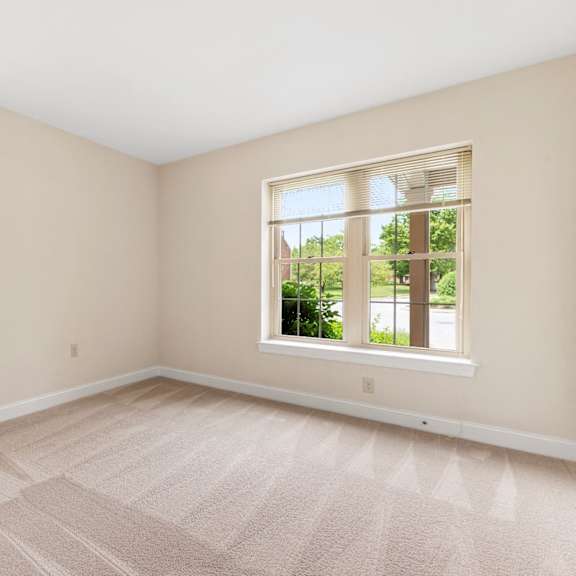 a bedroom with neutral carpet flooring and two windows providing ample natural light.