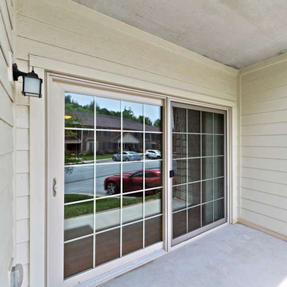 the exterior view of a patio with an outdoor light and large sliding glass doors to a living room.