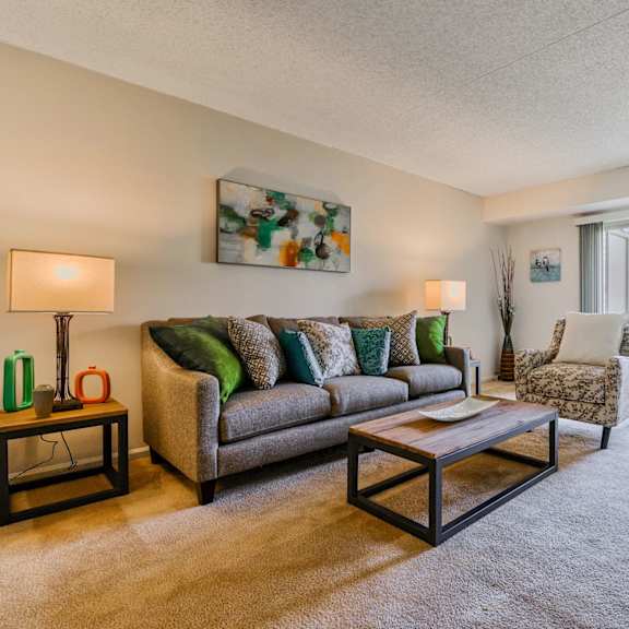 a cozy living room with plush carpet flooring and natural light from sliding glass doors to a private patio.