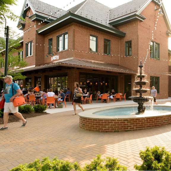 a beautiful courtyard fountain at the eagleview town center with people sitting at outdoor restaurant tables, near shops in exton, pa.