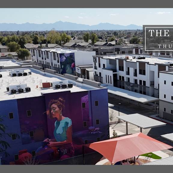a woman is sitting on a balcony of a building with a mountain in the background.