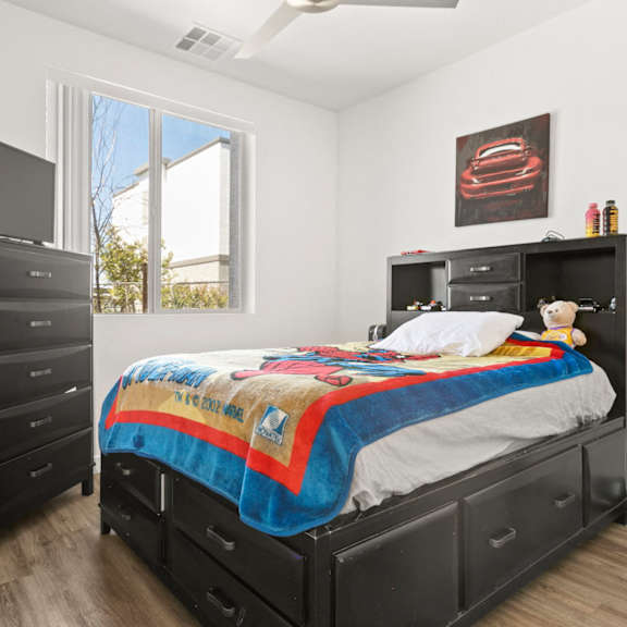 a bedroom with a bed, dresser, and tv.