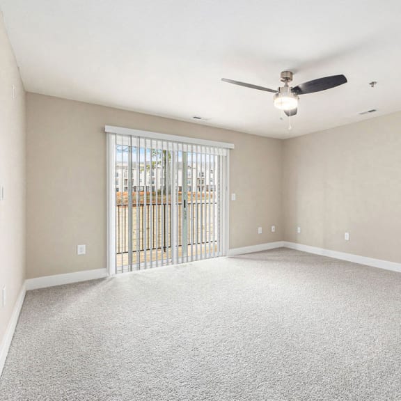 Thumbnail 4 of 17 Spacious living room with ceiling fan and slider to balcony at Eagle Ridge Apartment Homes,  Michigan