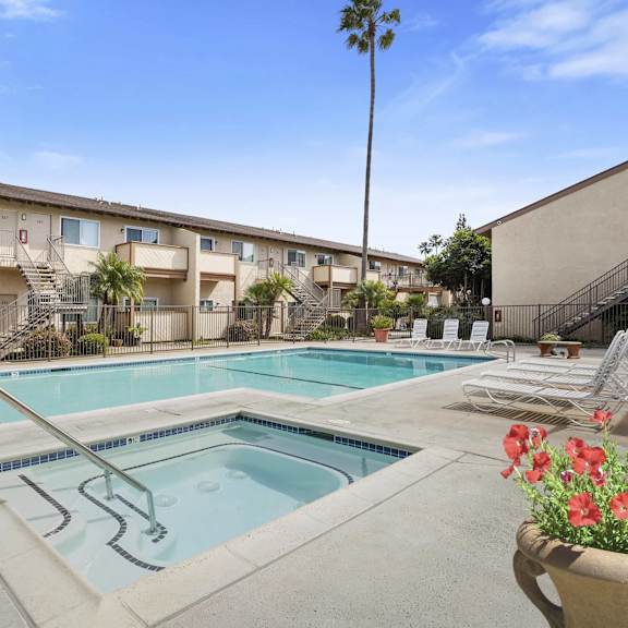a pool surrounded by chairs and a building in the background.