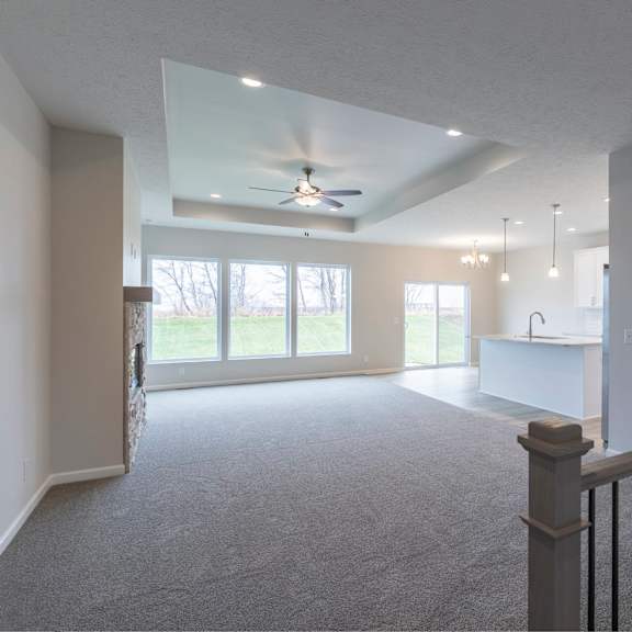 a spacious living room with a ceiling fan and sliding glass doors.