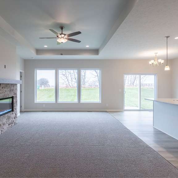 a spacious living room with a fireplace and a ceiling fan.
