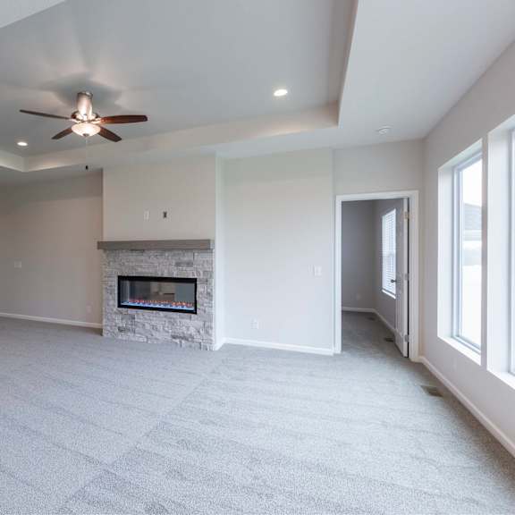 a spacious living room with a fireplace and a ceiling fan.