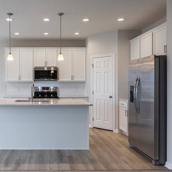 a modern kitchen with a stainless steel refrigerator and a white island.
