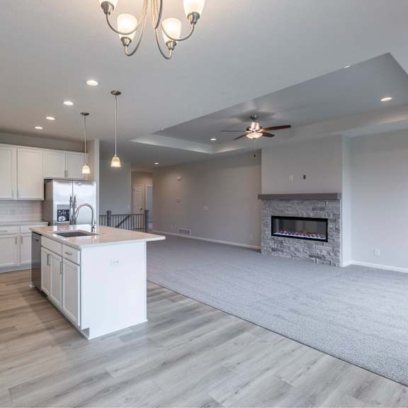 a modern kitchen with a white island and a fireplace.