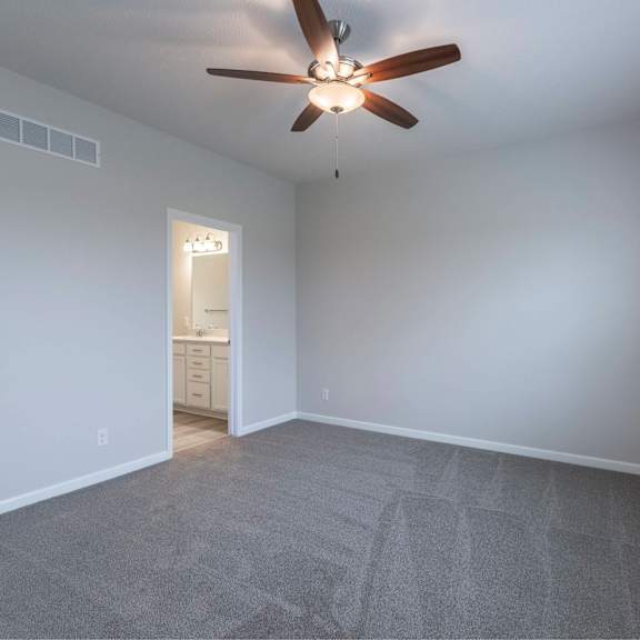 a room with a ceiling fan and carpeted floor.