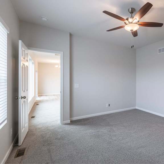 a room with a ceiling fan and carpeted floor.