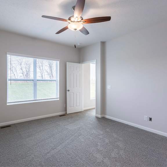 a room with a ceiling fan and a window with blinds.