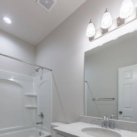 a white bathroom with a toilet, sink, and mirror.