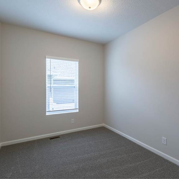 a room with a carpeted floor and a window with blinds.
