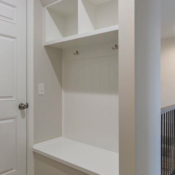 a white door is on the left of a white shelving unit.