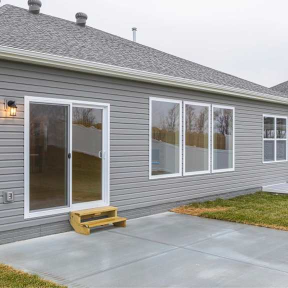 a grey house with a white fence and a grey roof.