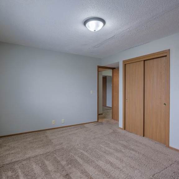 room with tan carpet and brown closet doors.
