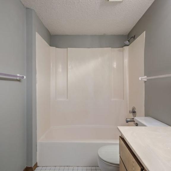 a white toilet sits next to a bathtub in a bathroom.
