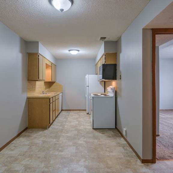 a kitchen with a refrigerator, sink, and cabinets.