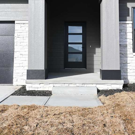a modern house with a stone facade and a large glass door.