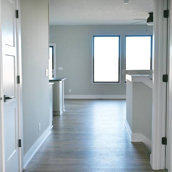 a long, narrow hallway with a white door on the left and a white door on the right.