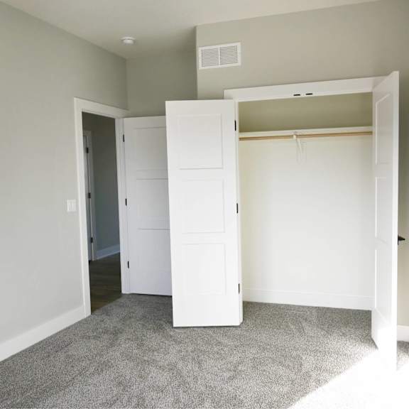 a room with a white closet and carpeted floor.