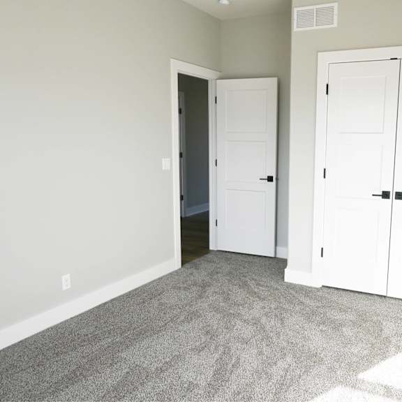 a room with a grey carpet and two white doors.