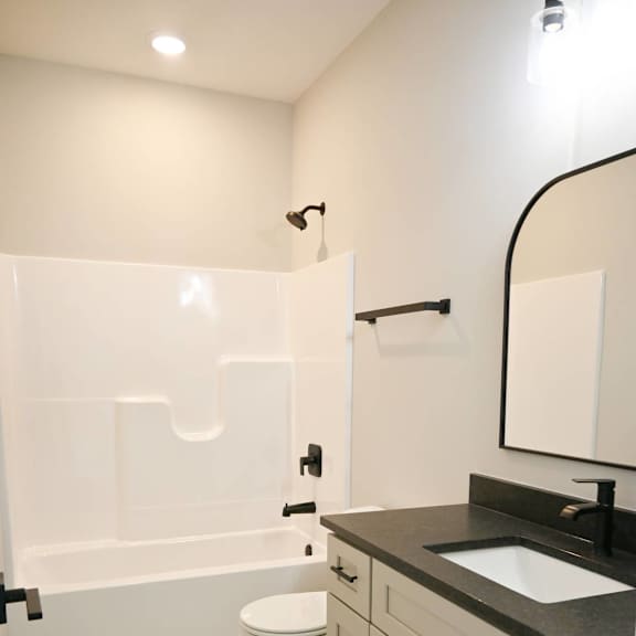 a white toilet sits in a bathroom with a black counter top.