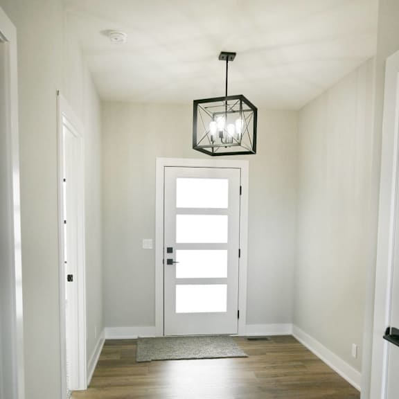 a hallway with a light hanging from the ceiling and a door at the end.