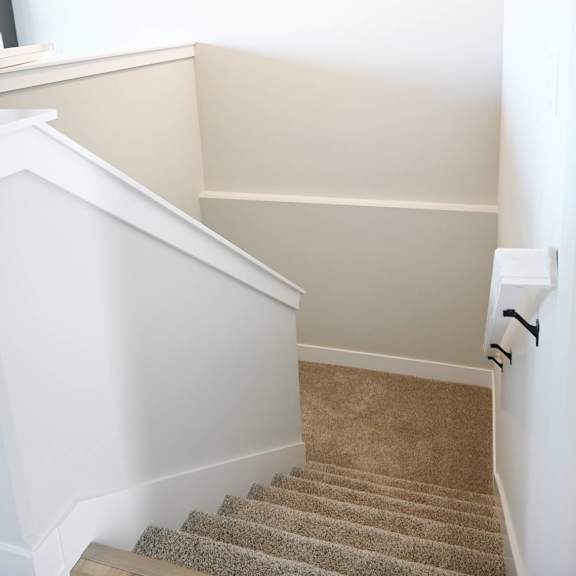 a staircase with a beige carpet and white walls.